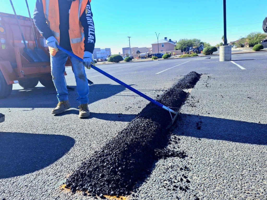 Worker spreading fresh asphalt repair